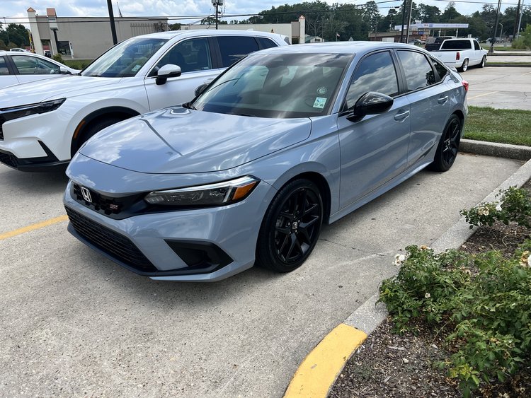 A blue car parked in a parking lot next to other cars