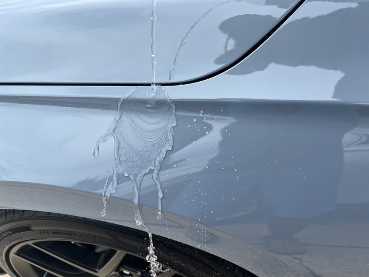 A close up of a car's front tire with water coming out of it