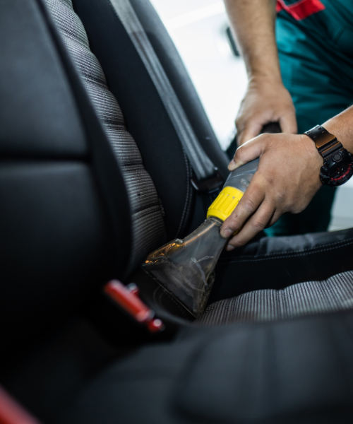 A man cleaning a car seat with a sponge